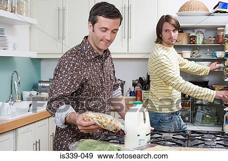Gay couple putting food in the fridge View Large Photo Image Stock Photo - Gay couple putting food in the fridge. Fotosearch
