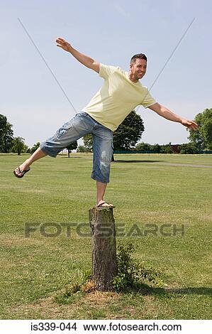 Picture - Man balancing on tree stump. Fotosearch