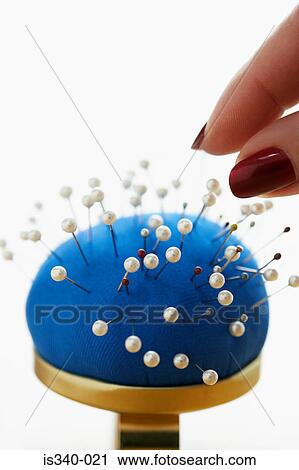 Stock Image - Woman taking pin from pincushion. Fotosearch