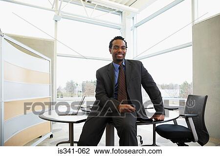 Stock Image - Businessman sitting on desk. Fotosearch