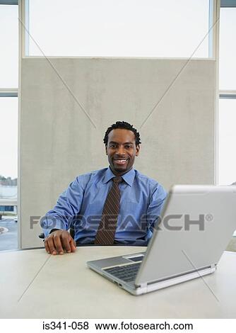 Man at his desk with laptop View Large Photo Image Stock Photo - Man at his desk with laptop. Fotosearch