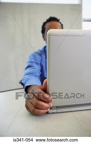 Picture - Man behind laptop. Fotosearch