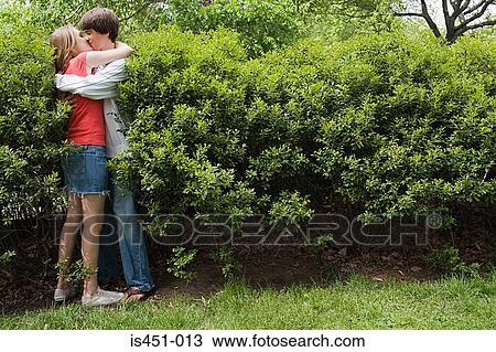 Stock Image - Teenage couple kissing in bush. Fotosearch