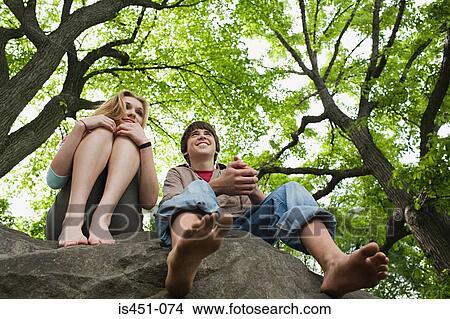 Teenage couple relaxing on a rock View Large Photo Image Picture - Teenage couple relaxing on a rock. Fotosearch