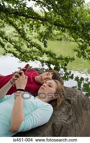 Picture - Teenage couple using a cellular telephone. Fotosearch