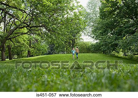 Teenage couple walking in a park View Large Photo Image Stock Photo - Teenage couple walking in a park. Fotosearch