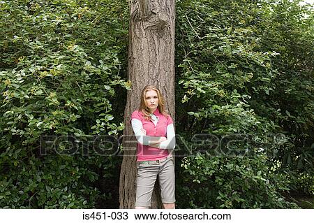 Teenage girl standing against a tree View Large Photo Image Stock Image - Teenage girl standing against a tree. Fotosearch