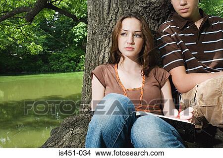 Teenagers sitting by a tree View Large Photo Image Picture - Teenagers sitting by a tree. Fotosearch