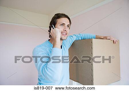 Stock Photo - Man on mobile phone with cardboard box. Fotosearch
