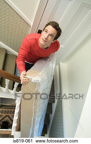 Man on stairs with a mattress View Large Photo Image Stock Image - Man on stairs with a mattress. Fotosearch