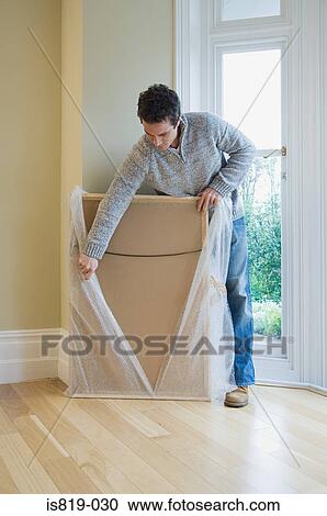 Stock Image - Man unwrapping a picture frame. Fotosearch