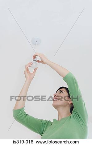 Woman changing a lightbulb View Large Photo Image Stock Photograph - Woman changing a lightbulb. Fotosearch