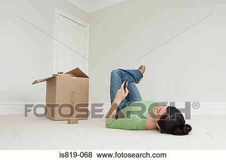 Woman lying on floor with cellphone and cardboard box View Large Photo Image Stock Photo - Woman lying on floor with cellphone and cardboard box. Fotosearch