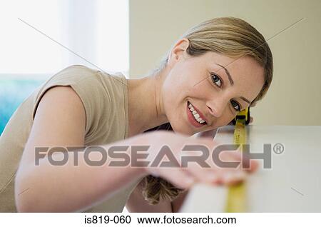 Stock Image - Woman measuring a shelf. Fotosearch