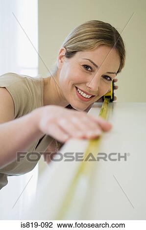 Woman measuring a shelf View Large Photo Image Stock Image - Woman measuring a shelf. Fotosearch