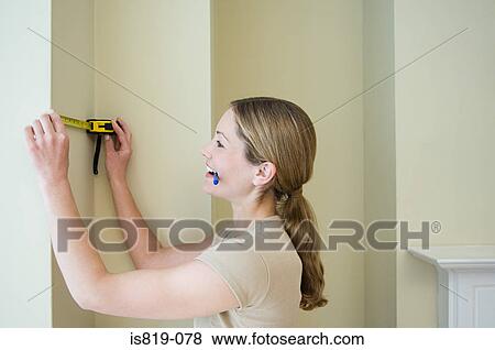 Stock Photo - Woman measuring a wall. Fotosearch