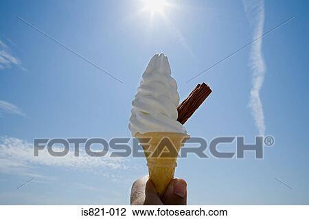 Stock Image - Person holding an ice cream cone. Fotosearch