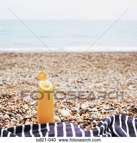 Stock Image - Suntan lotion on shingle beach. Fotosearch