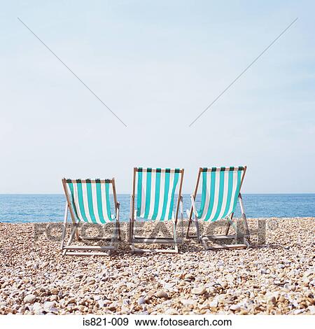 Three deckchairs on a shingle beach View Large Photo Image Stock Photo - Three deckchairs on a shingle beach. Fotosearch