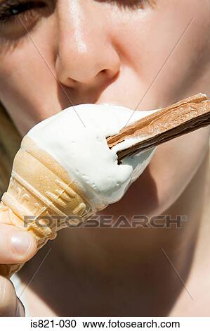 Stock Image - Young woman eating an ice cream. Fotosearch