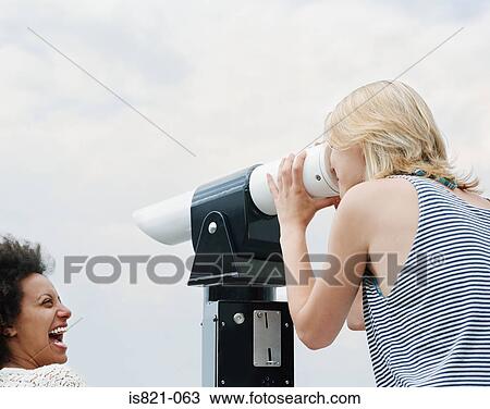 Young women looking through a telescope View Large Photo Image Stock Image - Young women looking through a telescope. Fotosearch