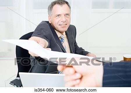 Stock Image - Businessman handing over a piece of paper. Fotosearch