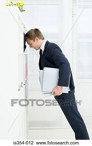 Stock Image - Businessman leaning on shelves. Fotosearch