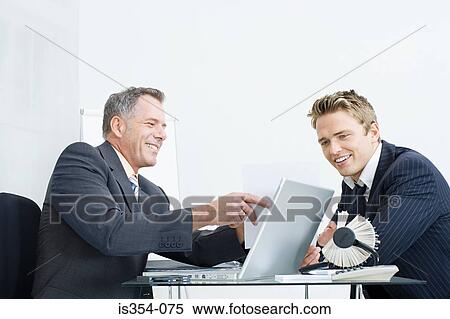 Businessmen sitting at desk View Large Photo Image Stock Photography - Businessmen sitting at desk. Fotosearch