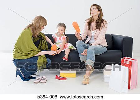 Stock Photo - Girl and mother with shoe shop assistant. Fotosearch