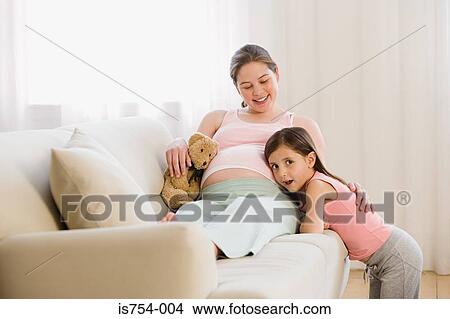 Daughter listening to mothers stomach View Large Photo Image Picture - Daughter listening to mothers stomach. Fotosearch