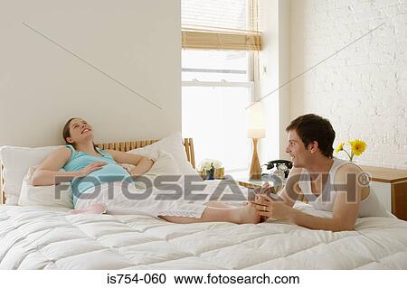 Stock Image - Man massaging pregnant partners foot. Fotosearch