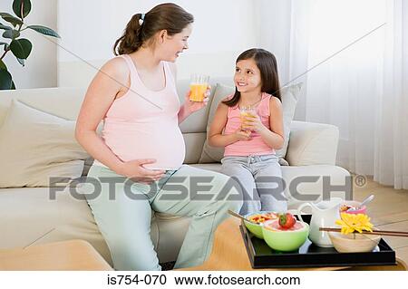 Stock Image - Mother and daughter holding glasses of orange juice. Fotosearch