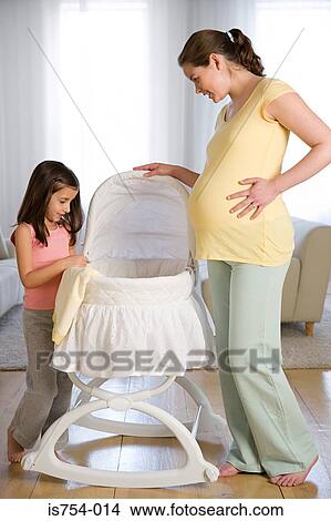 Mother and daughter looking at a crib View Large Photo Image Picture - Mother and daughter looking at a crib. Fotosearch