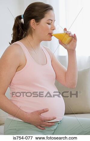 Pregnant woman drinking orange juice View Large Photo Image Stock Photo - Pregnant woman drinking orange juice. Fotosearch