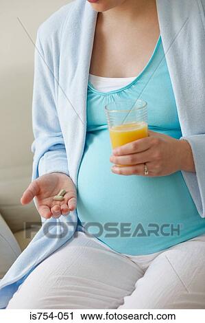 Pregnant woman holding vitamin pills and orange juice View Large Photo Image Stock Image - Pregnant woman holding vitamin pills and orange juice. Fotosearch
