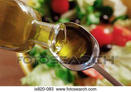 Stock Image - Olive oil pouring on to a spoon. Fotosearch
