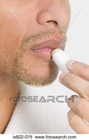 Stock Photography - Man putting on lip balm. Fotosearch