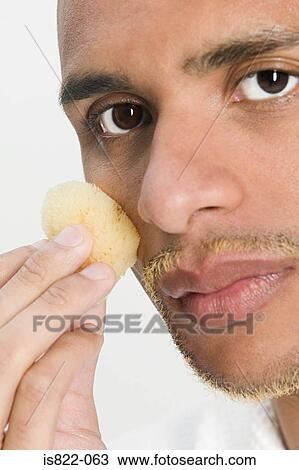 Stock Image - Man using sponge on his face. Fotosearch
