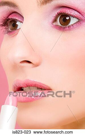 Stock Image - Woman applying pink lipstick. Fotosearch