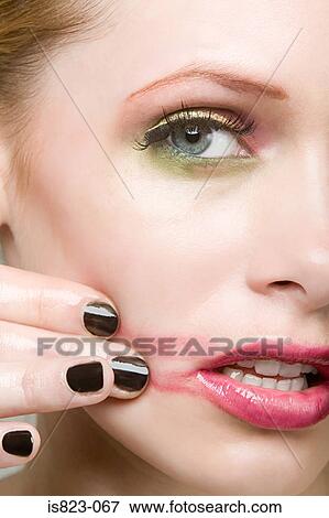 Woman smearing lipstick on face View Large Photo Image Stock Photo - Woman smearing lipstick on face. Fotosearch