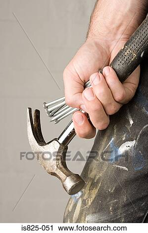Stock Image - Man holding hammer and nails. Fotosearch