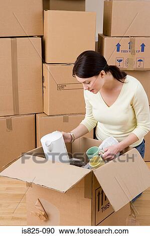 Stock Image - Woman unpacking cups and kettle. Fotosearch