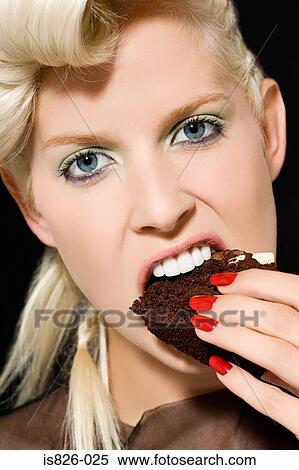 Stock Photography - Woman biting a slice of cake. Fotosearch