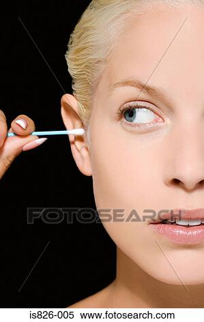 Stock Photography - Woman putting cotton bud in her ear. Fotosearch