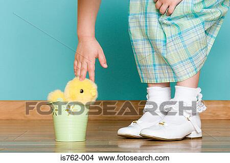 Picture - Girl stroking a soft toy chick. Fotosearch
