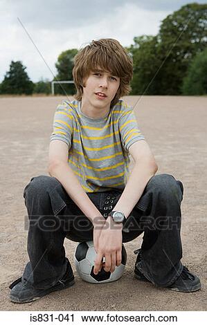 Stock Image - Boy sitting on a football. Fotosearch