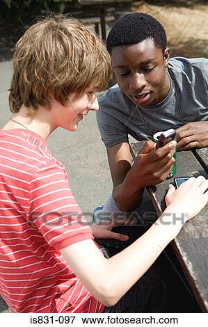 Teenage boys looking at cellphone View Large Photo Image Stock Photo - Teenage boys looking at cellphone. Fotosearch