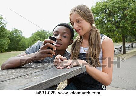 Teenage couple looking at cellphone View Large Photo Image Stock Photo - Teenage couple looking at cellphone. Fotosearch