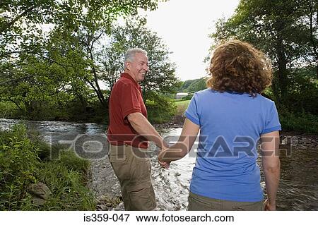 Mature couple crossing a stream View Large Photo Image Stock Photo - Mature couple crossing a stream. Fotosearch