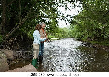 Stock Image - Mature couple fishing in stream. Fotosearch